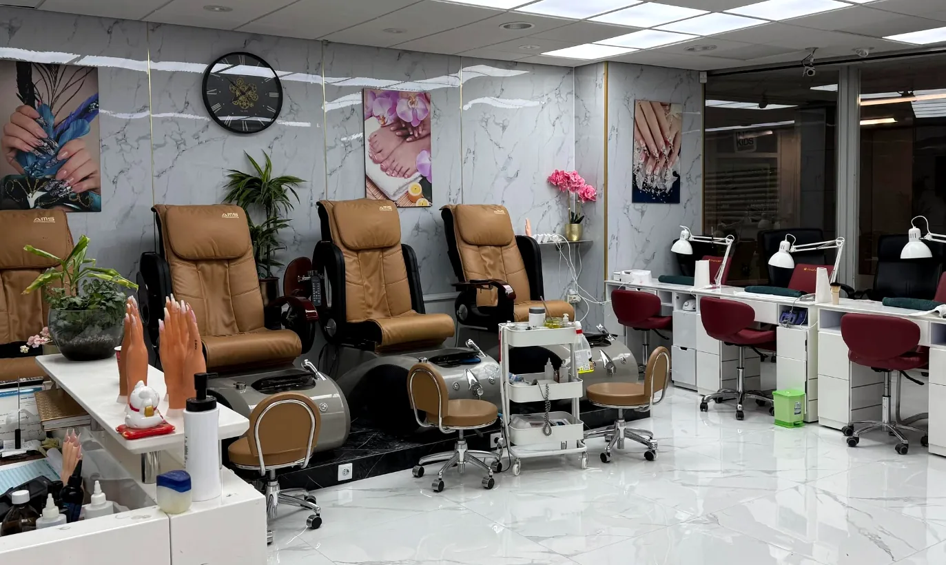 Overzicht van de salon met pedicurestoelen en nageltafels op een marmeren vloer
